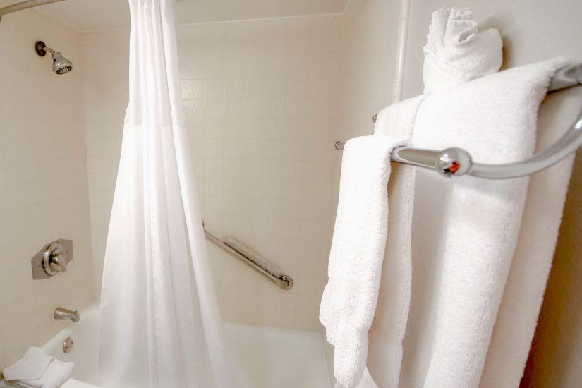 Photo of the bathroom with a white curtain and white towels