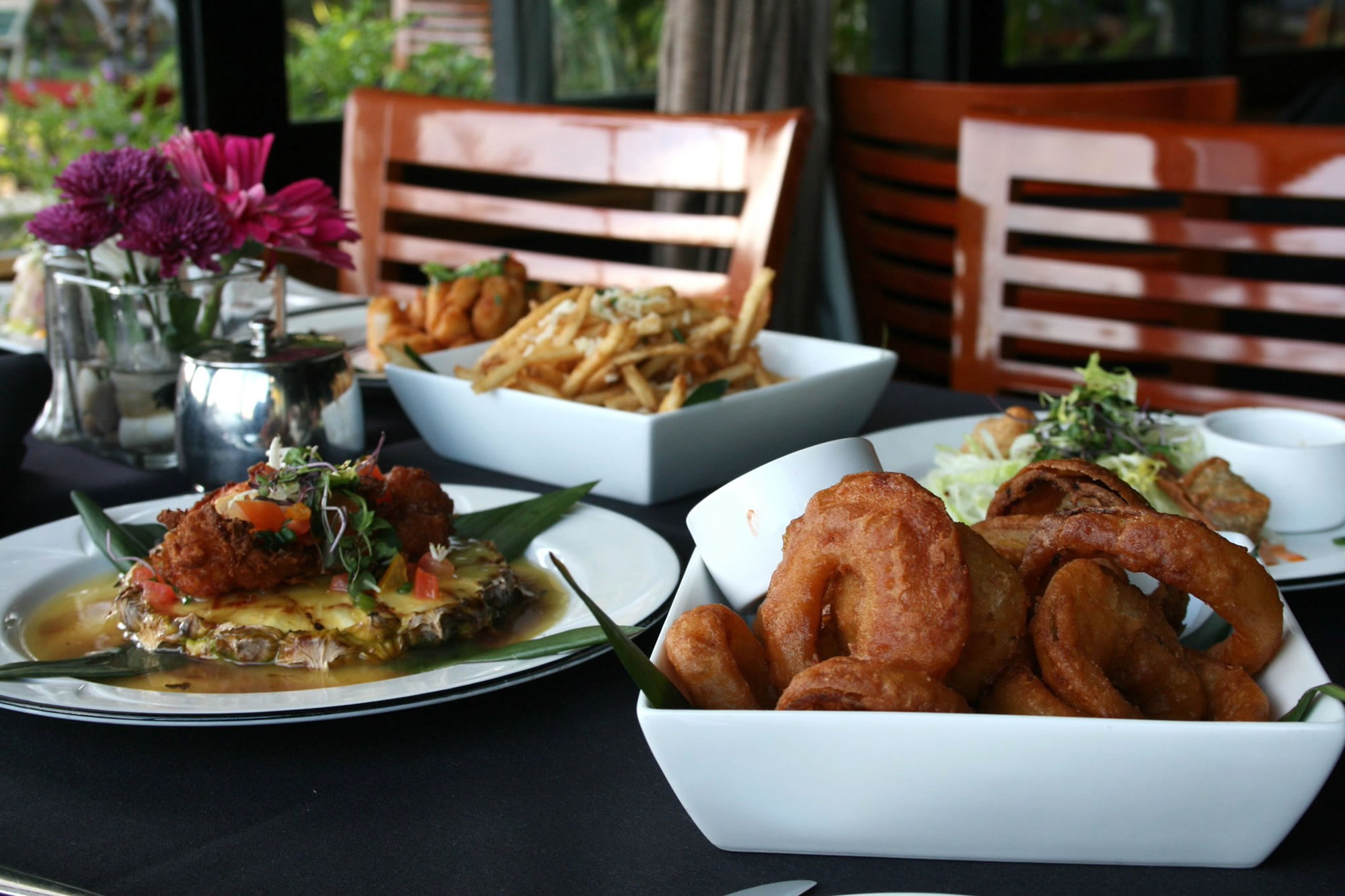 A table set with various dishes of food, including fried onion rings and a salad.